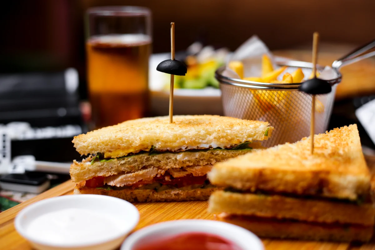 Crispy French toast sandwich cut in half with toothpick skewers, served with fries and a cold beverage.