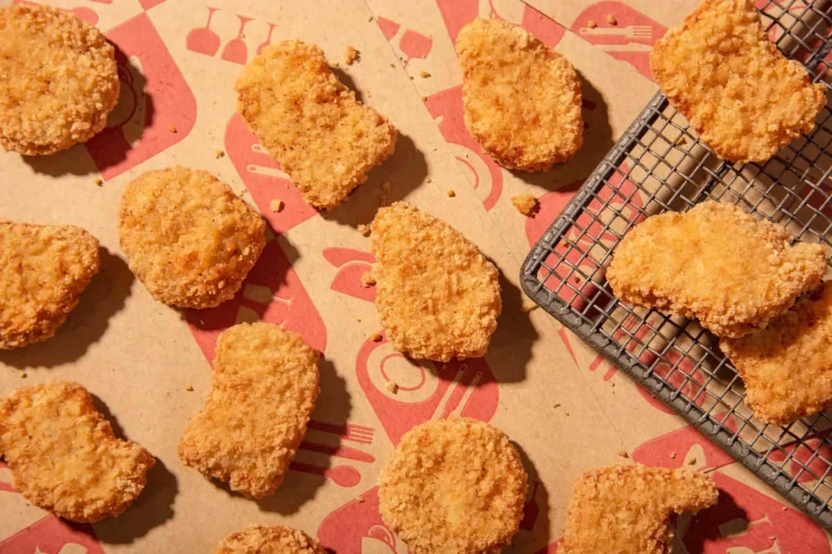 Freshly baked chicken nuggets spread on parchment paper with a patterned background.