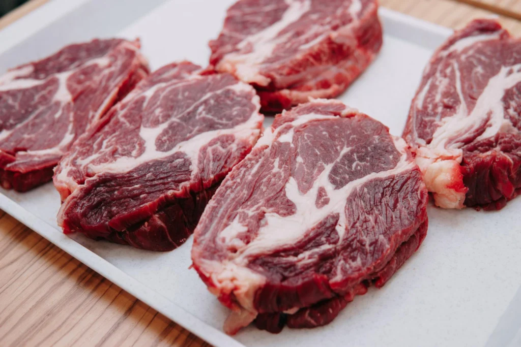 Fresh raw beef cuts on a white tray, resembling the initial stage in crafting deli meats similar to Sopressata or Capicola.