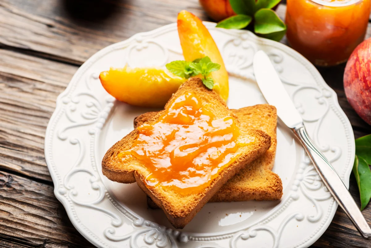 Golden toasted bread with orange marmalade on an elegant white plate