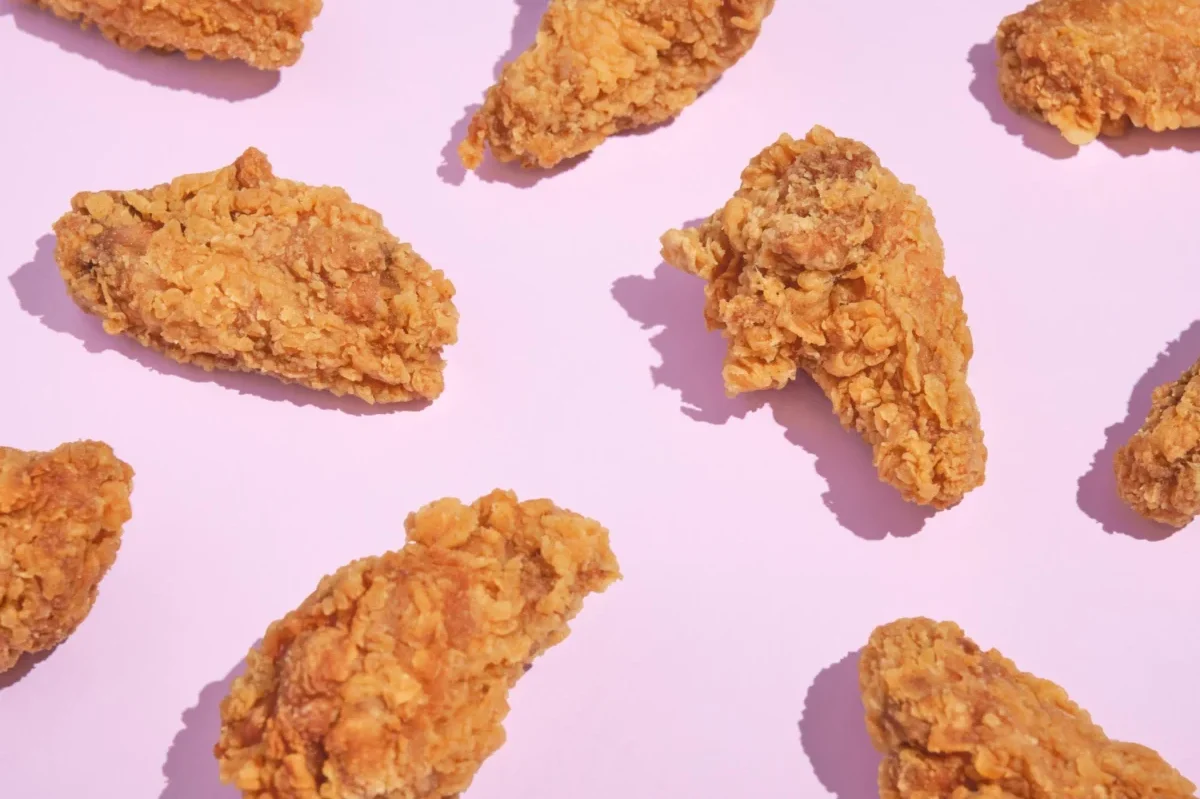 Crispy fried chicken pieces arranged on a pink background.