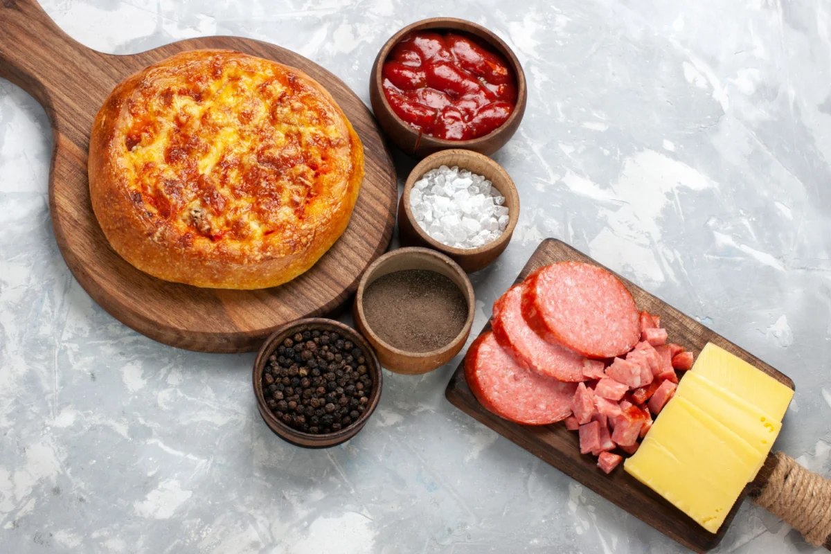 Homemade pizza with ingredients including pepperoni, cheese, and spices, inviting the question: Is pepperoni and Sopressata the same thing?