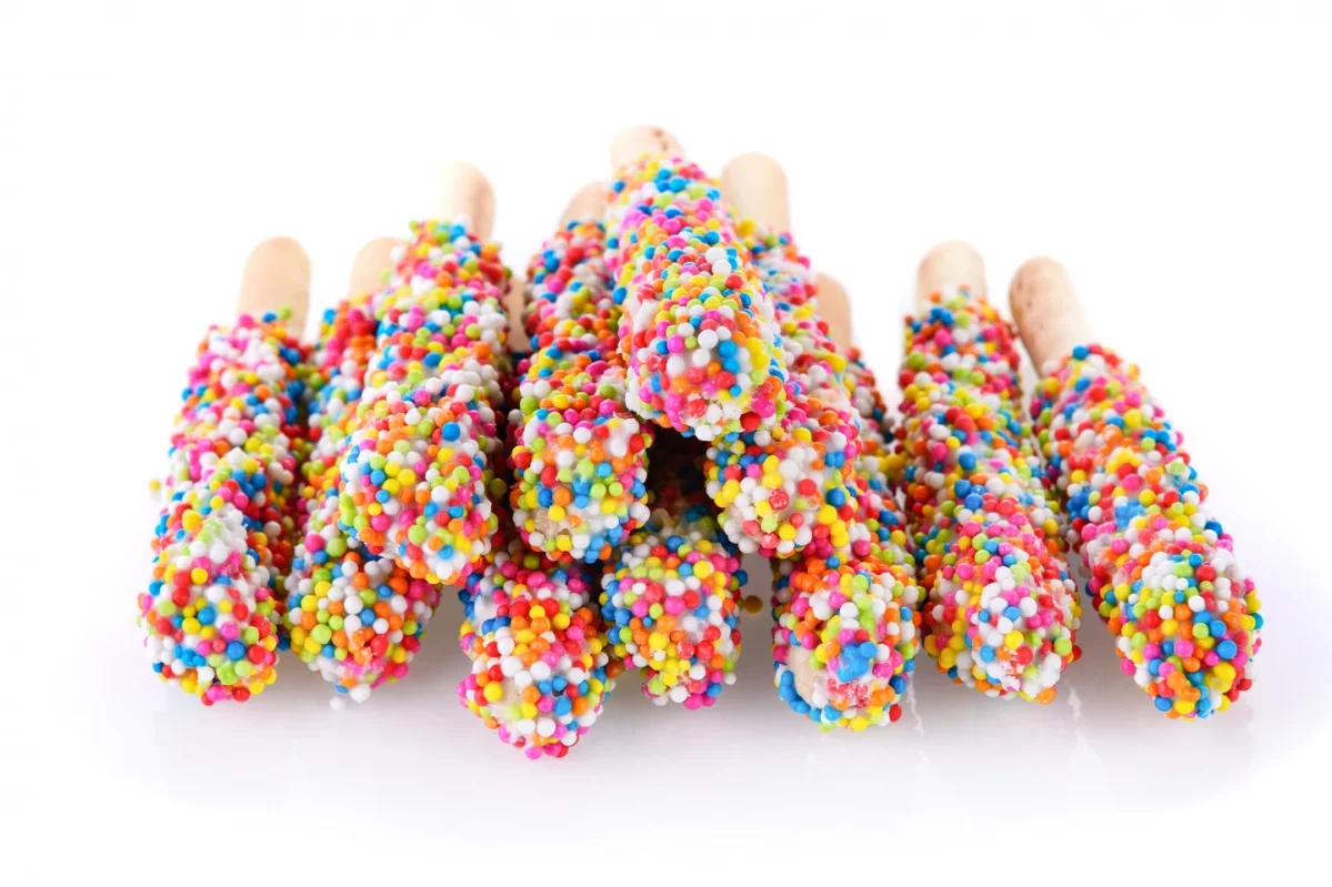 Brightly colored candy-coated ice cream pops on sticks, clustered together against a white background.