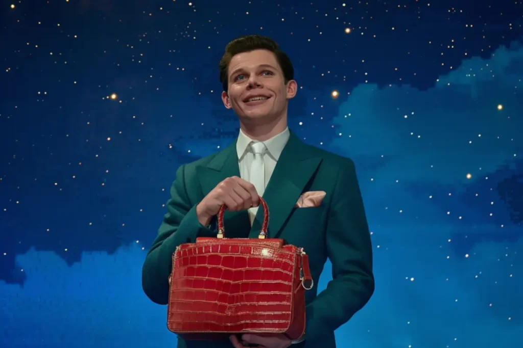 Host of "Is It Cake?" holding a hyper-realistic cake shaped like a red handbag against a starry background.